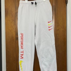 White Nike kids sweatpants, orange and yellow writing and Nike symbols